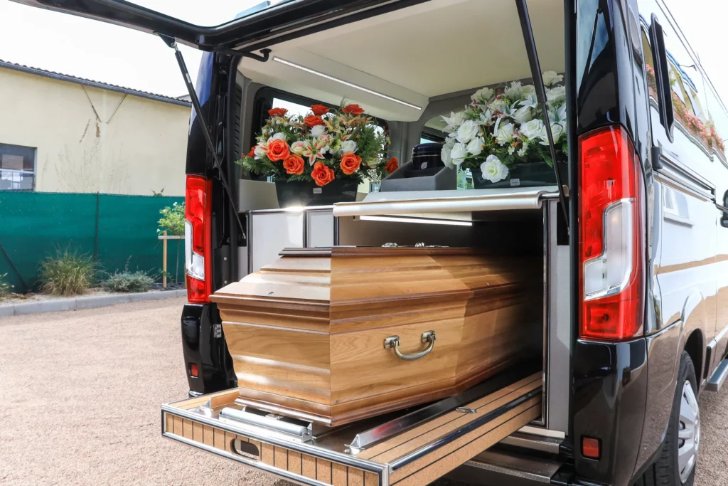 Cercueil en bois posé dans un corbillard lors d'un transport funèbre.