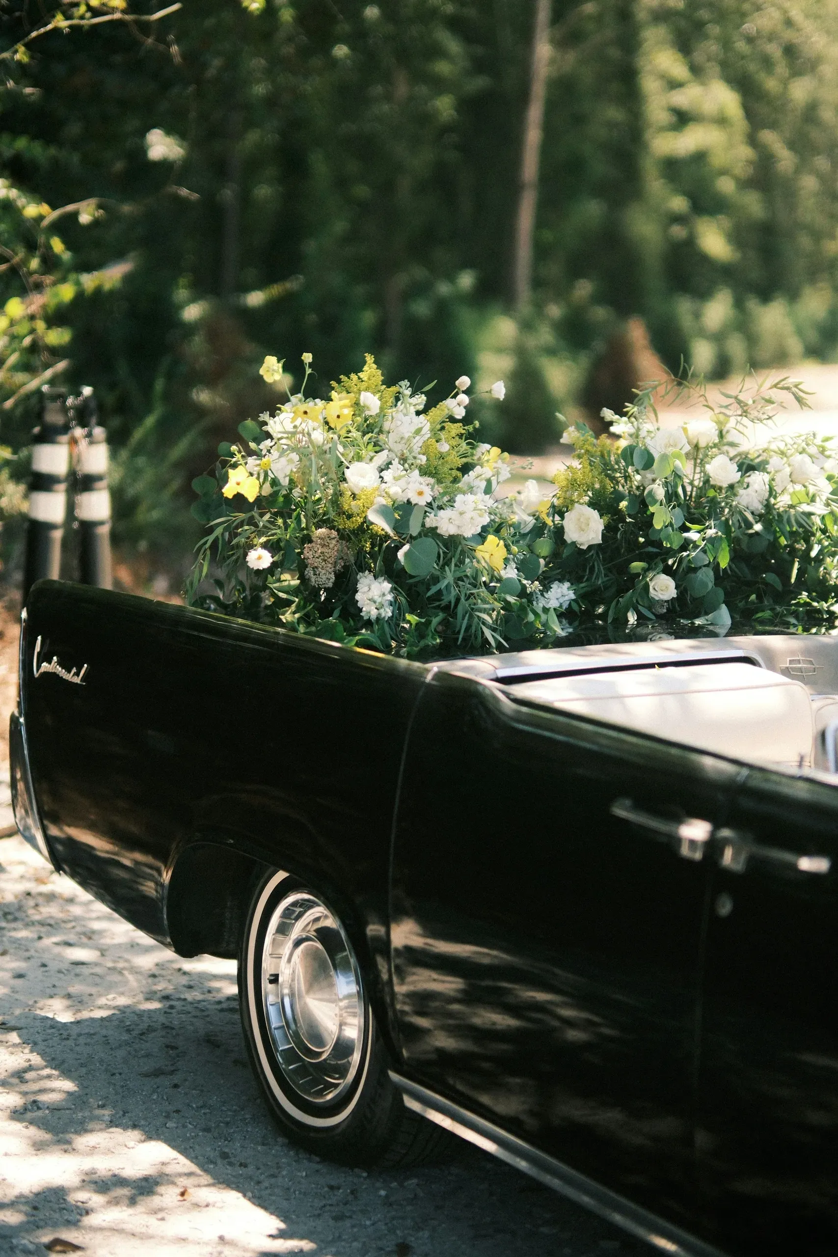 Véhicule de cortège funèbre vintage orné de compositions florales.